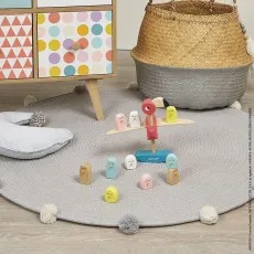 A Janod toucan balancing toy on a gray pom-pom rug, with some of the bird pieces off the scale
