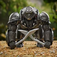 The Optimus Primal gorilla robot toy posed with two translucent weapons on a jungle floor.