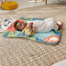 A smiling baby in a white sleeper lies on their back on a panda-themed tummy time mat