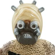 A close-up of a Tusken Warrior action figure's head and shoulders, showing its mask and head spikes.