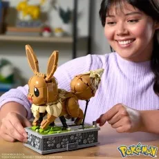 A smile girl using a handle to make the brick-built Eevee figure move on its display base.