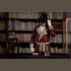 A detailed toy figure of the Invisible Man posed at a desk with a book and flask.