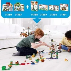 Two kids playing on the floor with a large, combined LEGO Super Mario course.