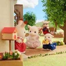 A close-up of the Sylvanian Families goat daughter and son figurines greeting a rabbit figure on a front porch.