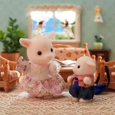 The daughter and son goat figures from Sylvanian Families standing together in a dollhouse room.