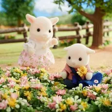 The son and daughter goat figurines from Sylvanian Families in a garden with flowers.