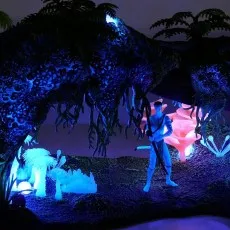 A glowing Avatar toy scene in a dark setting, showing a figure, plants, and an arch with bright blue lights.