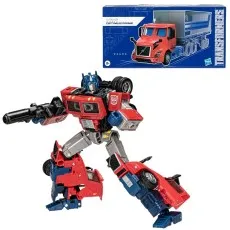 Transformers Optimus Prime (Volvo VNR) action figure in robot mode, wielding a blaster, next to its box.