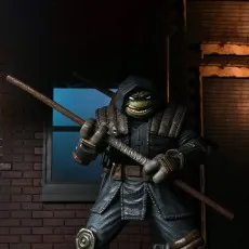Close-up of the hooded Last Ronin action figure with a menacing smile, wielding a long wooden bo staff