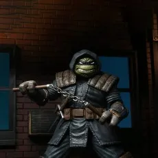 The Last Ronin (TMNT) action figure in a dark hooded cloak, holding nunchaku in a shadowy alley