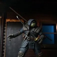The Last Ronin action figure in a hooded cloak, holding a katana and sai, posed in a dark alley diorama
