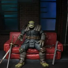 The Last Ronin action figure seated on a worn red couch in an alley diorama, surrounded by his weapons