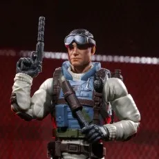 Action figure of Airborne in his helmet and night vision goggles, aiming a gun in a dark arena.