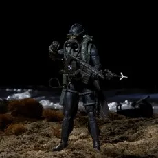 Action figure of a military diver in a wetsuit, helmet, and rebreather, holding an underwater rifle on a dark beach.