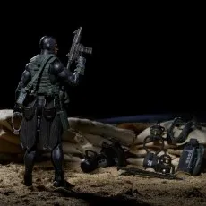Action figure of a recon diver in a black suit holding a rifle, with diving gear laid out on a sandy ground