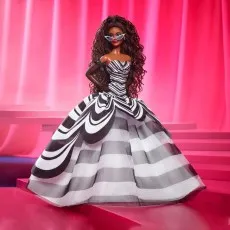 Barbie 65th Anniversary Signature doll in a black and white striped gown and sunglasses on a pink set.