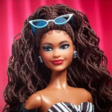 Close-up of Barbie doll face brown hair, blue eyeshadow, red lips, and white cat-eye sunglasses on her head.