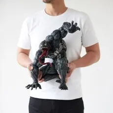 A man in a white shirt holds a large, detailed Venom statue with its tongue and claws visible.