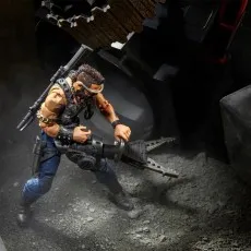 G.I. Joe Dreadnok Ripper figure kneeling and using a large mechanical cutting tool near a vehicle tire.