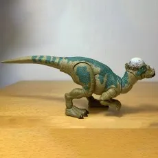 Articulated Pachycephalosaurus figure from the Jurassic Park Hammond Collection against a white wall.