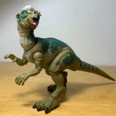 Close-up of the Pachycephalosaurus toy showing its green and tan color pattern and open mouth.