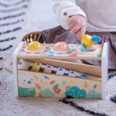A child plays with the Janod Tap Tap Xylo toy, using the bee-headed mallet to pound a ball into the xylophone.