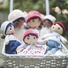 Close-up of several diverse Kaloo fabric dolls sitting in a white basket.